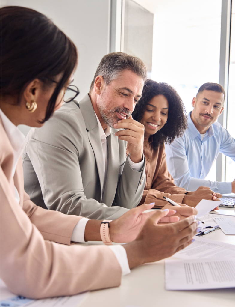 Primer plano de dos personas dándose la mano sobre una mesa con dos maquetas de casas pequeñas y un contrato,
